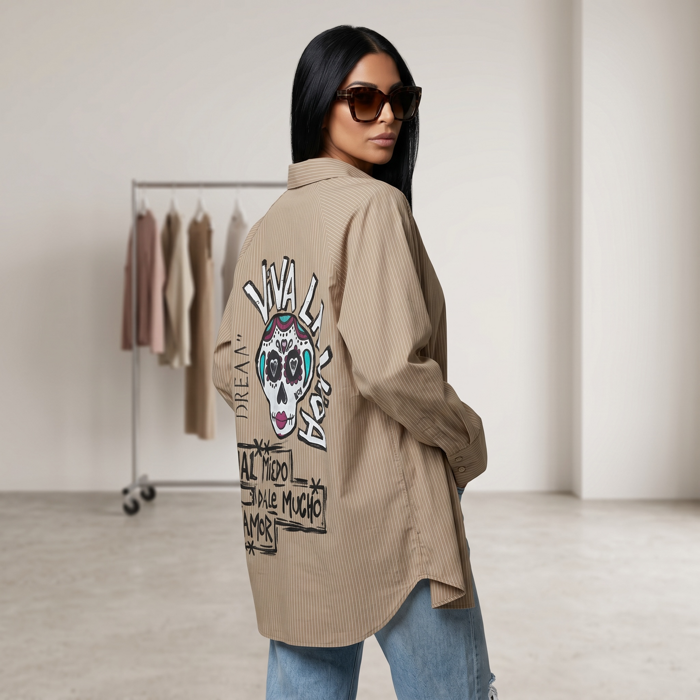 Camisa oversize beige de rayas finas pintada a mano en la espalda con ilustración estilo calavera mexicana y frase artística, diseño exclusivo de Paola Santos.