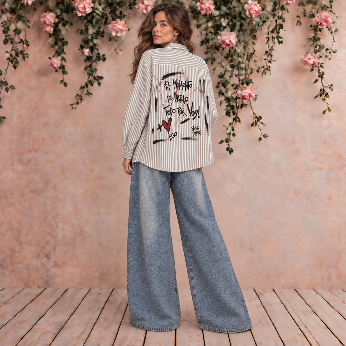 Camisa rayada beige y blanca de corte amplio con intervención artística y frase Es momento de darlo todo por vos en la espalda, diseño Paola Santos.
