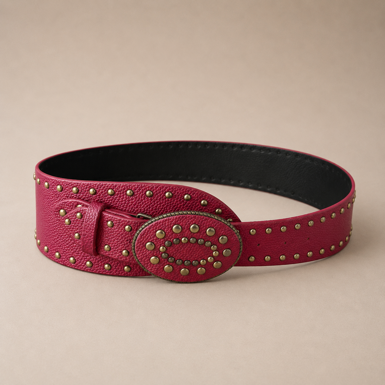 Cinto ancho color rojo con textura simil cuero, detalles de tachas metálicas y hebilla oval decorativa en acabado bronce, ideal para completar looks urbanos y sofisticados.