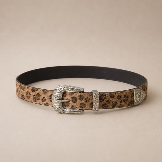 Cinto fino animal print en tonos camel y negro con hebilla metálica plateada estilo western y detalles grabados.